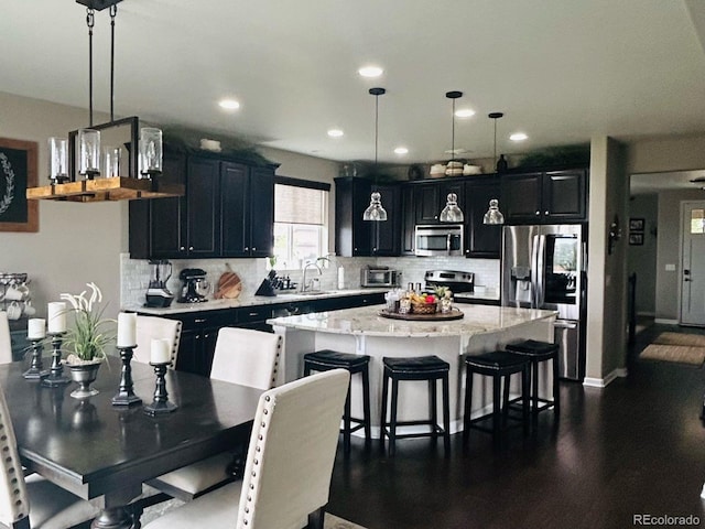 kitchen featuring appliances with stainless steel finishes, a center island, dark cabinets, and a kitchen bar