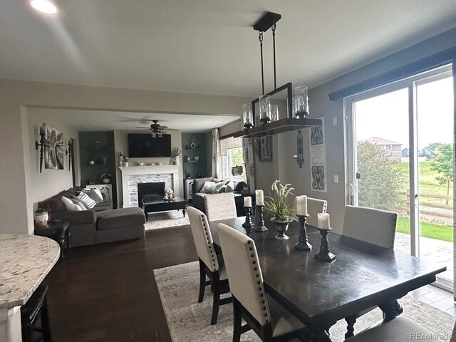 dining room featuring a fireplace, a ceiling fan, and wood finished floors