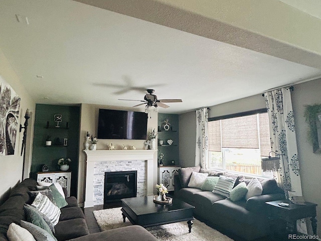 living room with a glass covered fireplace and ceiling fan