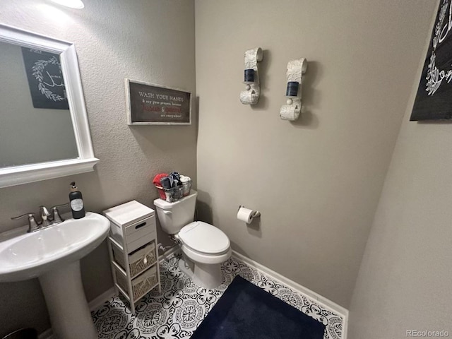 bathroom with tile patterned flooring, baseboards, a sink, and toilet