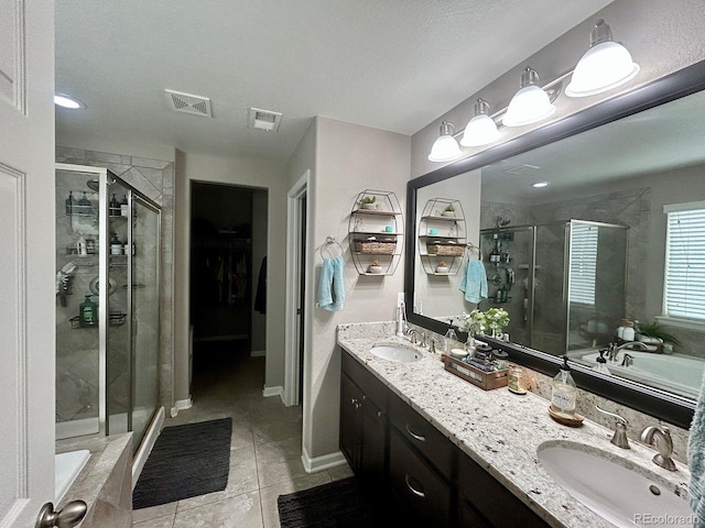 bathroom with a textured ceiling, dual vanity, tile patterned floors, and independent shower and bath