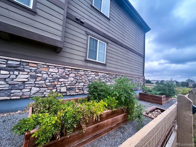 view of side of property featuring stone siding and a garden