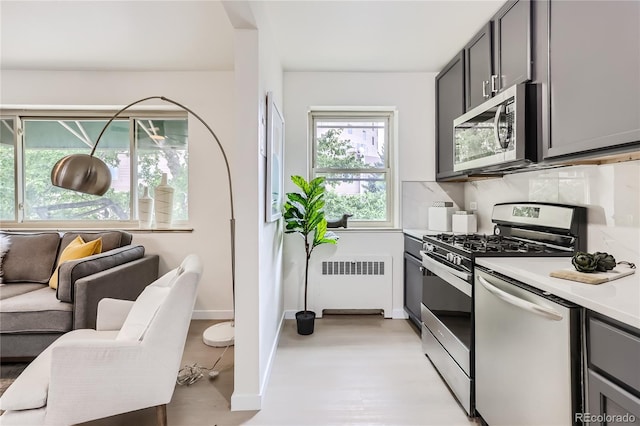 2100 N Franklin St Unit 20, Denver, CO 80205 - kitchen with stainless steel appliances, radiator heating unit, light countertops, light wood-style floors, and gray cabinetry