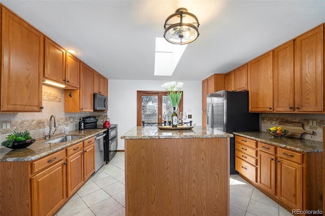 kitchen with light tile patterned flooring, a skylight, a sink, appliances with stainless steel finishes, and a center island