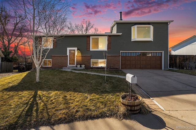 view of front facade with a garage, brick siding, fence, concrete driveway, and a lawn