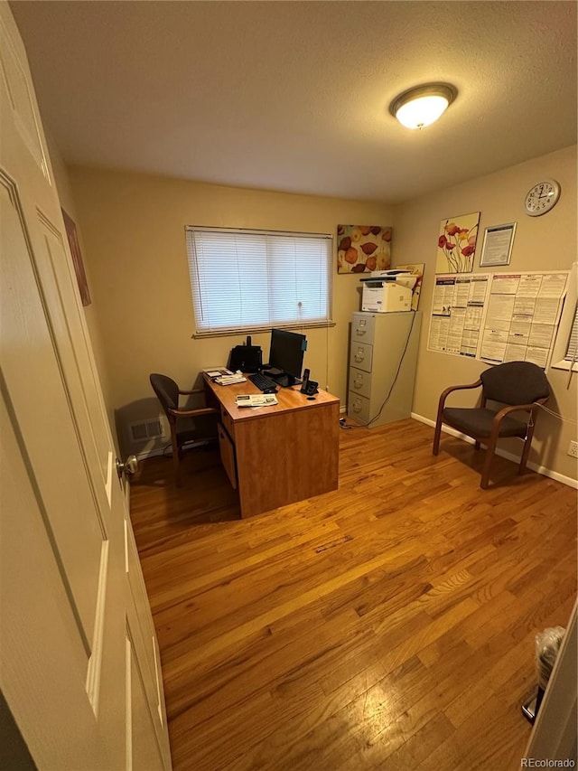 office space featuring a wall mounted AC, light hardwood / wood-style floors, and a textured ceiling