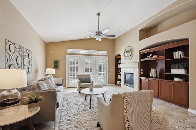 living area featuring light tile patterned flooring, built in features, lofted ceiling, ceiling fan, and a fireplace
