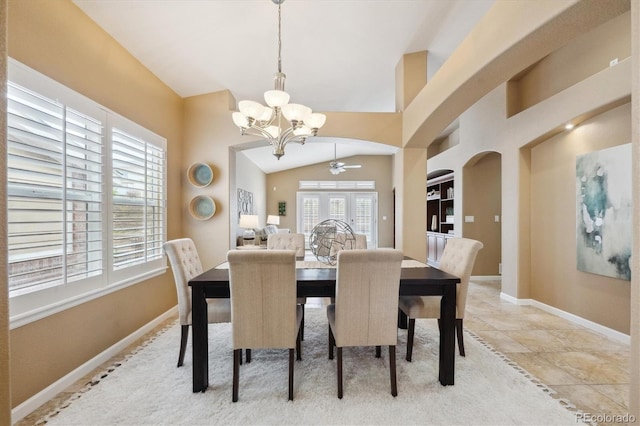 dining space with arched walkways, baseboards, vaulted ceiling, and ceiling fan with notable chandelier
