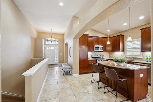kitchen with light stone counters, stainless steel appliances, a sink, arched walkways, and tasteful backsplash