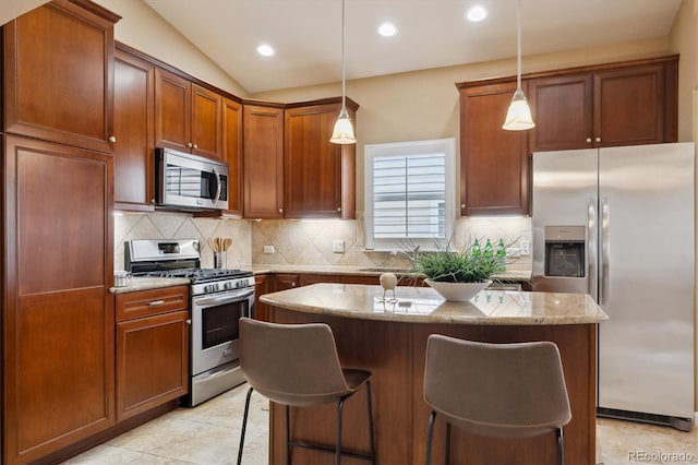 kitchen with stainless steel appliances, a center island, decorative backsplash, light stone counters, and a breakfast bar