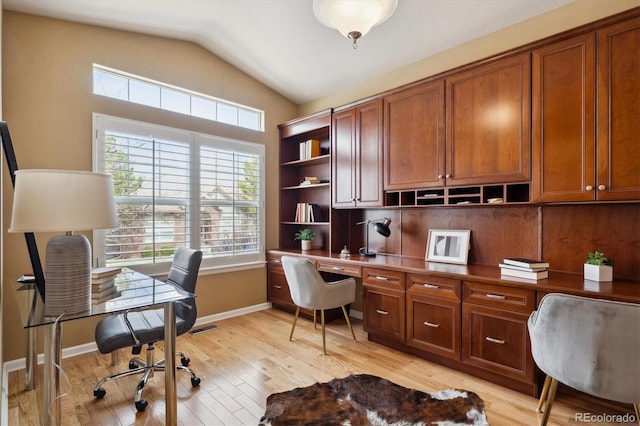 home office with built in desk, light wood finished floors, baseboards, lofted ceiling, and visible vents