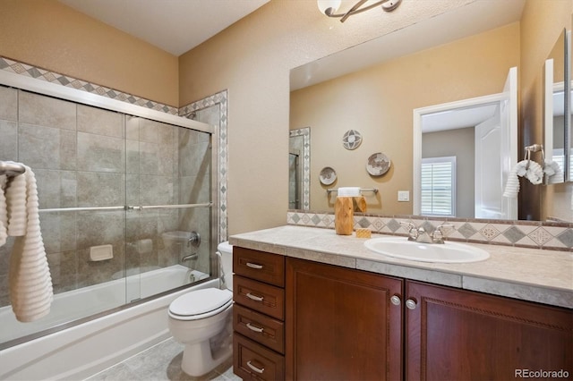 bathroom with vanity, toilet, and bath / shower combo with glass door