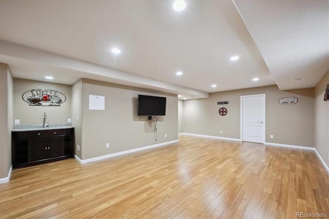 finished below grade area with recessed lighting, wet bar, light wood-type flooring, and baseboards