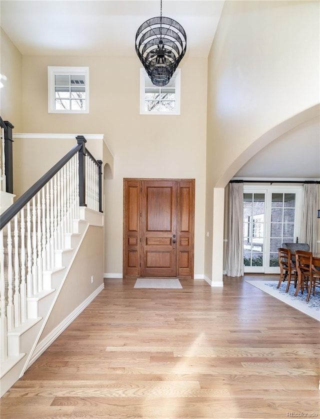 foyer entrance with a chandelier, light hardwood / wood-style flooring, and a high ceiling