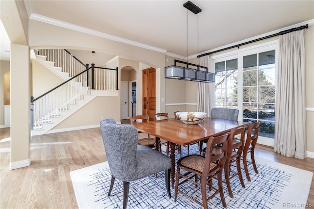 dining space with ornamental molding and light hardwood / wood-style floors