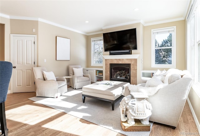 living room with ornamental molding, a tiled fireplace, and light hardwood / wood-style flooring