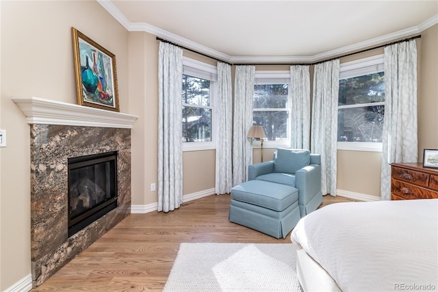 bedroom featuring crown molding, a fireplace, and light hardwood / wood-style floors