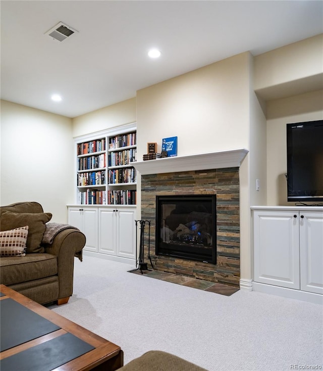 living room with a stone fireplace and dark carpet