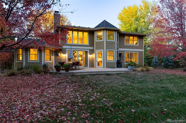 rear view of house featuring a lawn and a patio