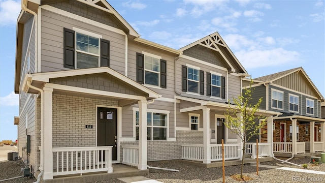 view of front facade with central AC, a porch, and brick siding