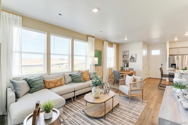 living area with baseboards, light wood finished floors, and recessed lighting