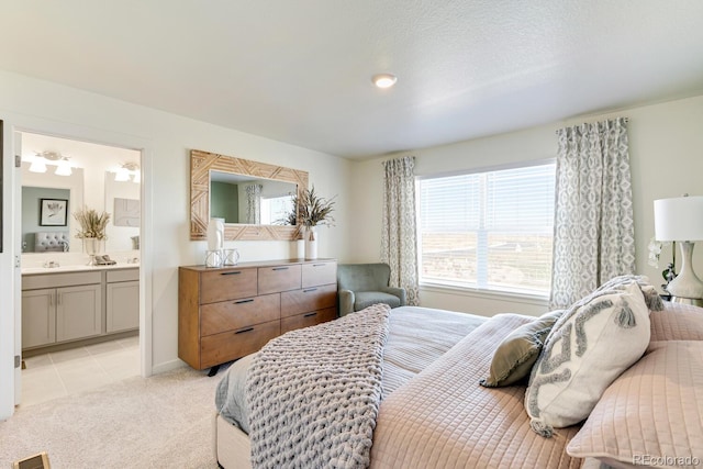 bedroom with light tile patterned floors, ensuite bath, and light colored carpet