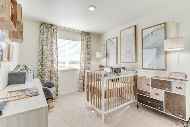 bedroom with a crib, baseboards, and carpet flooring