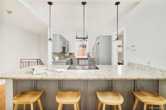 730 Cook St, Denver, CO 80206 - kitchen featuring freestanding refrigerator, black electric stovetop, a peninsula, a sink, and a kitchen breakfast bar