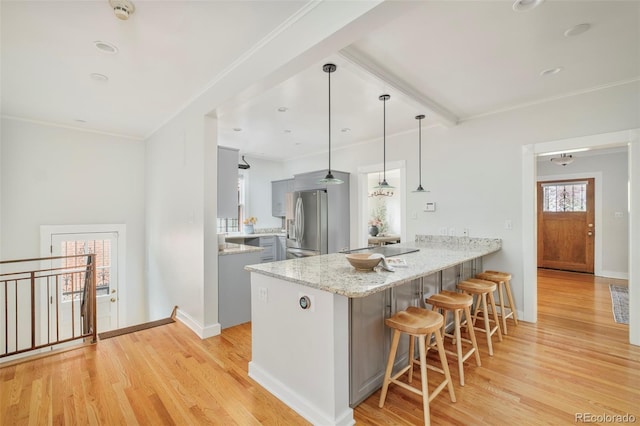 730 Cook St, Denver, CO 80206 - kitchen featuring stainless steel fridge, a peninsula, a breakfast bar, light wood-style floors, and gray cabinetry