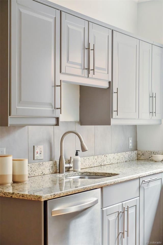 730 Cook St, Denver, CO 80206 - kitchen with stainless steel dishwasher, white cabinets, a sink, and decorative backsplash
