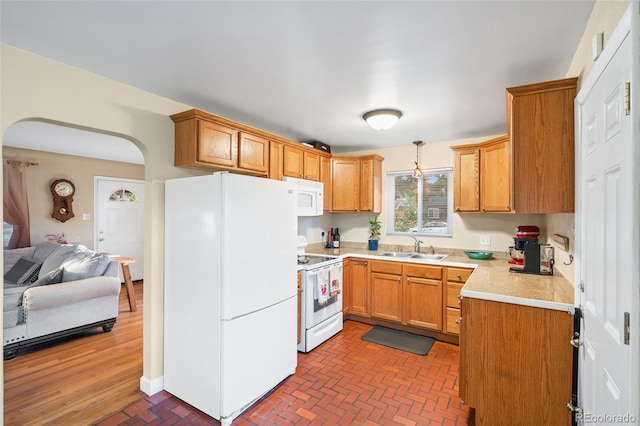 kitchen featuring sink, pendant lighting, and white appliances