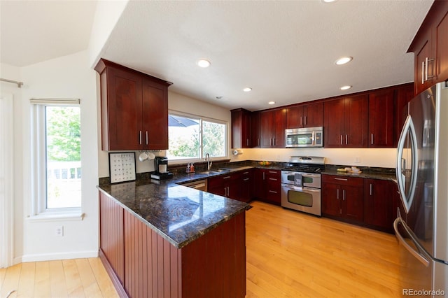 1881 Alma Ln, Superior, CO 80027 - kitchen with stainless steel appliances, a peninsula, dark brown cabinets, light wood finished floors, and dark stone countertops
