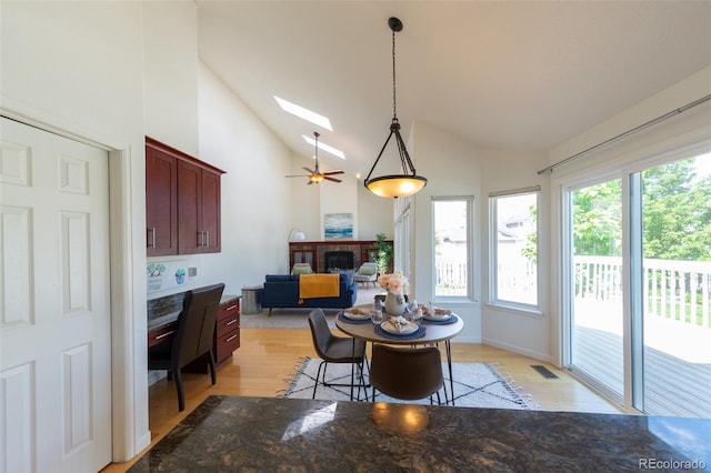 1881 Alma Ln, Superior, CO 80027 - dining room with vaulted ceiling, a fireplace, light wood-style floors, a skylight, and a ceiling fan