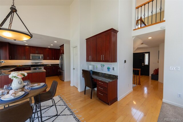 1881 Alma Ln, Superior, CO 80027 - kitchen featuring appliances with stainless steel finishes, a high ceiling, dark countertops, reddish brown cabinets, and recessed lighting
