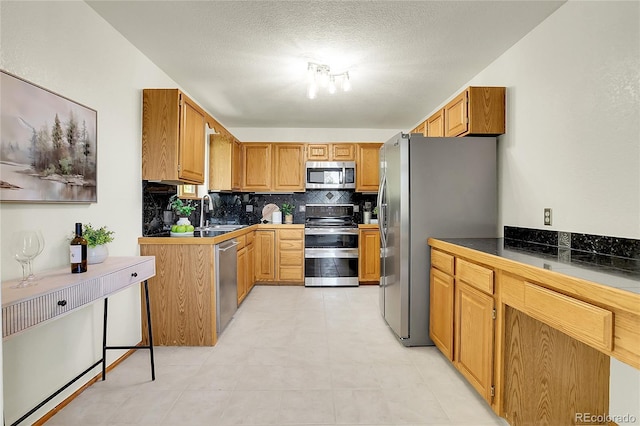 11333 Conifer Mountain Rd, Conifer, CO 80433 - kitchen featuring appliances with stainless steel finishes, tasteful backsplash, a textured ceiling, and brown cabinetry