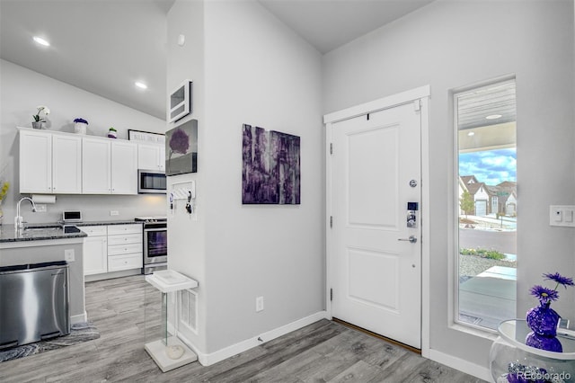 2742 Show Hunter Way, Colorado Springs, CO 80922 - kitchen featuring stainless steel appliances, a sink, light wood-type flooring, white cabinetry, and vaulted ceiling