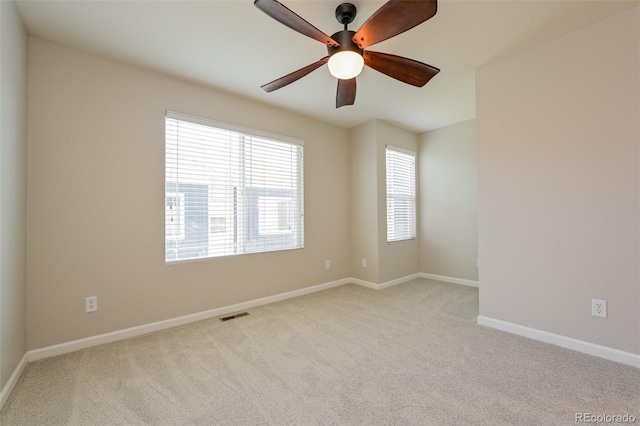 unfurnished room with ceiling fan, light colored carpet, baseboards, and visible vents