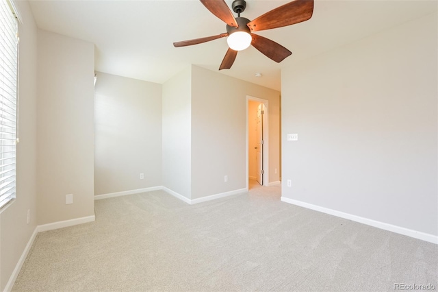unfurnished room with baseboards, a ceiling fan, light colored carpet, and a wealth of natural light