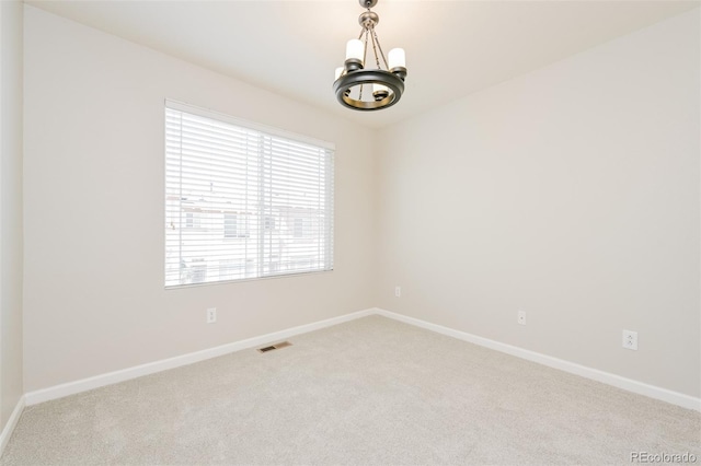 spare room featuring baseboards, a notable chandelier, visible vents, and carpet floors