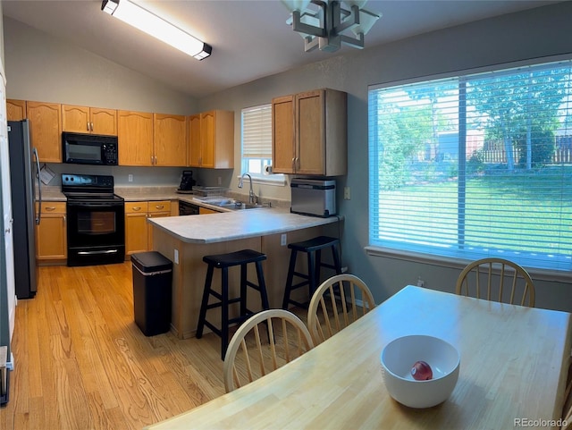 5201 E 127th Dr, Thornton, CO 80241 - kitchen with black appliances, a peninsula, lofted ceiling, light wood-style floors, and light countertops