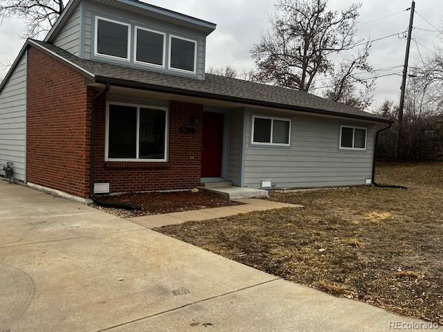 view of front of property featuring brick siding and roof with shingles