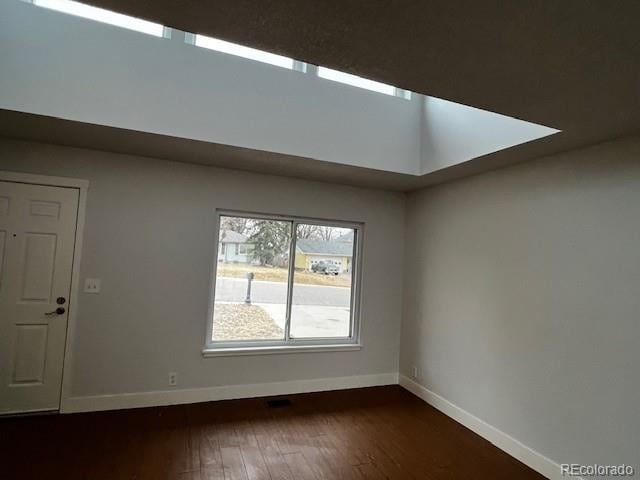 empty room with dark wood finished floors and baseboards