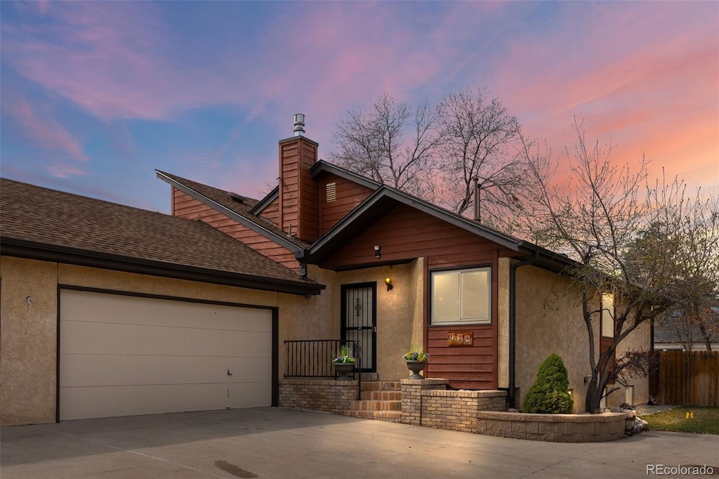 673 Brentwood St, Lakewood, CO 80214 - chalet / cabin featuring roof with shingles, a garage, stucco siding, a chimney, and driveway