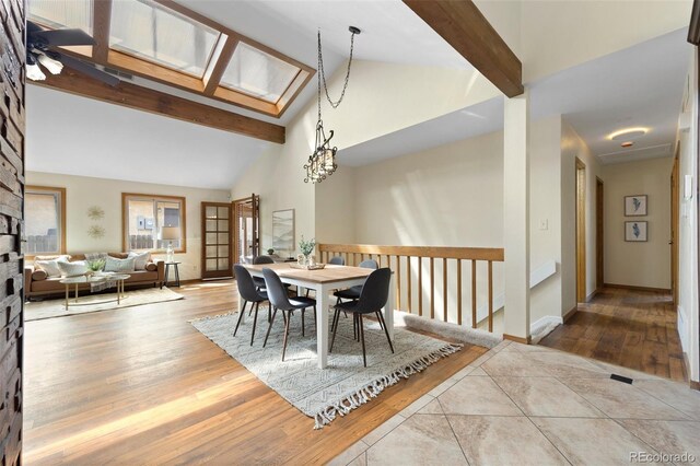 dining area with a skylight, wood finished floors, high vaulted ceiling, baseboards, and beamed ceiling