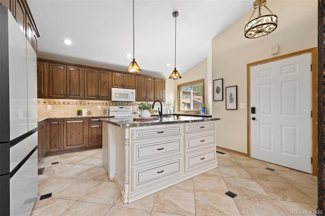 kitchen featuring white appliances, dark stone countertops, decorative light fixtures, lofted ceiling, and backsplash