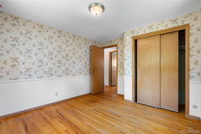 7135 S Sherman St, Centennial, CO 80122 - unfurnished bedroom featuring light wood-style floors, wallpapered walls, a wainscoted wall, and a closet