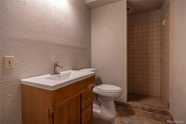 917 Bluebird Ln, Bailey, CO 80421 - bathroom with a tile shower, vanity, toilet, and a textured wall