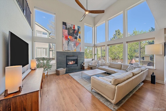 10127 W 100th Ct, Westminster, CO 80021 - living room featuring a towering ceiling, a ceiling fan, baseboards, a fireplace, and wood finished floors