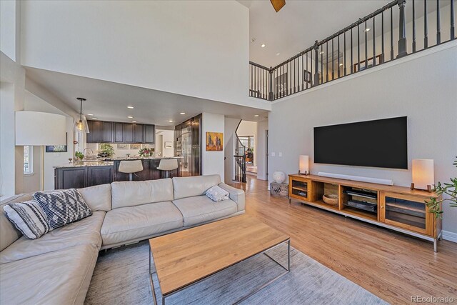 10127 W 100th Ct, Westminster, CO 80021 - living room featuring light wood-type flooring, a high ceiling, stairs, plenty of natural light, and recessed lighting