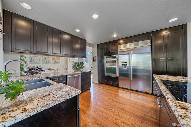 10127 W 100th Ct, Westminster, CO 80021 - kitchen with appliances with stainless steel finishes, a sink, light stone counters, light wood-style floors, and recessed lighting